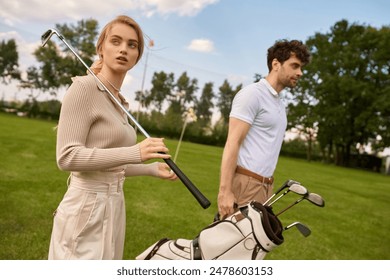 A stylish young man and woman in elegant attire walk leisurely on a lush green golf course, enjoying each others company. - Powered by Shutterstock