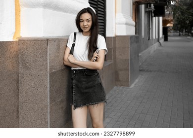 Stylish young pretty long hair brunette woman wearing white t-shirt, dark short jeans skirt and white modern sneakers having fun on the summer city street - Powered by Shutterstock