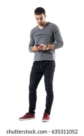 Stylish young trendy man typing message on cellphone. Full body length portrait isolated on white studio background. 