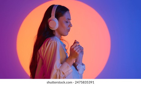 Stylish young woman in casual clothing listening music in headphones on smartphone and dancing. Isolated on colorful studio background spotlight. - Powered by Shutterstock