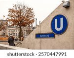 Stylish young woman exiting Bundestag underground station in Berlin Germany. Entrance to Bundestag Ubahn station with Reichstag in background. Public transportation concept