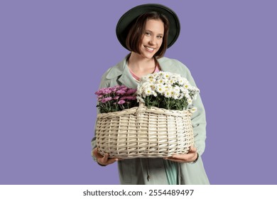 Stylish young woman holding basket with chrysanthemum flowers on lilac background - Powered by Shutterstock