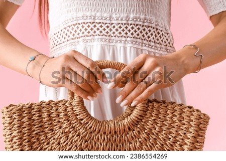 Stylish young woman with silver bracelets and bag on pink background, closeup