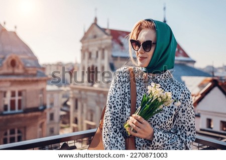 Stylish young woman wearing green retro shawl with sunglasses holding spring flowers. Classic vintage outdoor fashion [[stock_photo]] © 