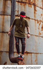 Stylishly dressed guy, on a rusty background in an abandoned place.
