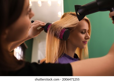 Stylist blow drying woman's hair in salon - Shutterstock ID 2006471255
