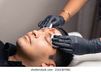 stylist cleaning a latin man's eyebrows after a micro pigmentation procedure