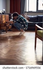 Stylist Guy Squatting And Looking For Something Among His Things In Drawer Stock Photo