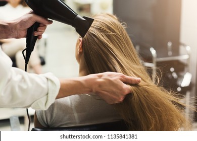 Stylist making hairstyle using hair dryer, blowing on wet customer hair at beauty salon, copy space