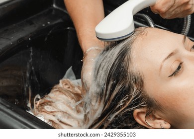 Stylist rinsing bleach to apply treatment to blonde hair. Woman in the beauty salon. Hairdresser and cosmetics. - Powered by Shutterstock