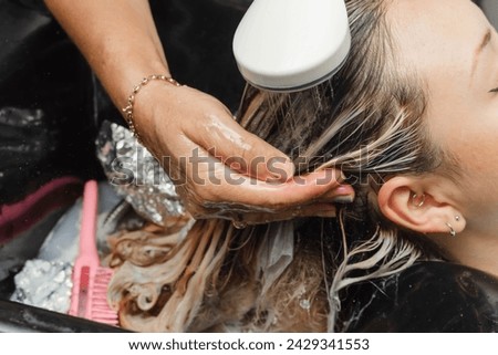 Stylist rinsing bleach and applying hair treatment. Hairdresser, client and cosmetics. Washing and rinsing.