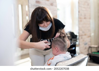 Stylist Shaves The Back Of The Head Of The Boy In The Barber Chair