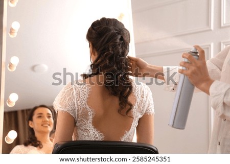 Stylist working with client in salon, making wedding hairstyle