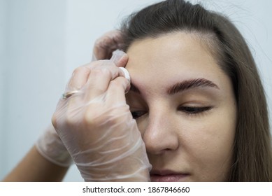 The Stylist's Hands In Gloves Wipe The Model's Face With A Cotton Pad.