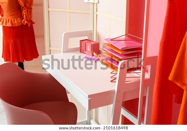 Stylist\'s workplace with notebooks and folding\
screen near pink wall