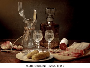 Stylized still life with a bottle of vodka or moonshine with a glass, bacon, sausage and cucumber. - Shutterstock ID 2262045155