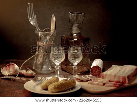 Stylized still life with a bottle of vodka or moonshine with a glass, bacon, sausage and cucumber. Foto stock © 