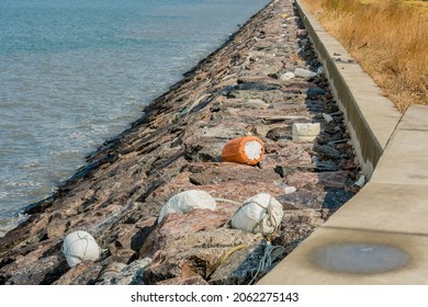 Styrofoam buoys laying on boulders on shoreline of ocean harbor.