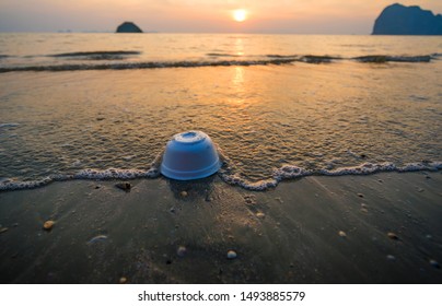 Styrofoam cup on tropical beach  pollutes the sea and marine life. Garbage rubbish trash problem environmental pollution. Concept of pollution control of the seas and oceans by single-use container.