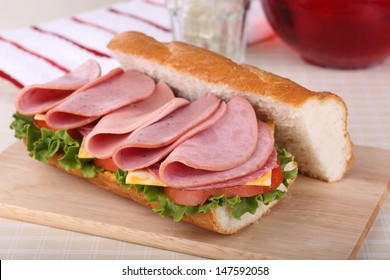 Sub Sandwich With Lunch Meat, Cheese, Lettuce And Tomato On A Wooden Tray