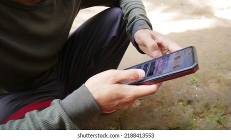 Suban Baru, Indonesia - 29 July 2022: Young Asian Man Using Phone And App Instagram, Scrolling Feed On Touchscreen With Finger, Social Media