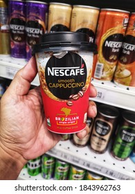 Subang Jaya, Malaysia - 23 October 2020 : Hand hold a cup of NESCAFE Smooth Cappuccino Milk Coffee Drink for sell in the supermarket with selective focus.