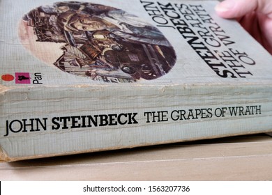 Subang Jaya, Malaysia - November 17, 2019: Hand Opening The Book By John Steinbeck, The Grapes Of Wrath. Set During The Great Depression, The Novel Tells About The Hardship Faced By The Joads Family.