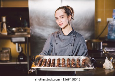 Subject profession and cooking pastry. young Caucasian woman with tattoo of pastry chef in kitchen of restaurant preparing round chocolate candies handmade truffle in black gloves and uniform. - Shutterstock ID 1569458545