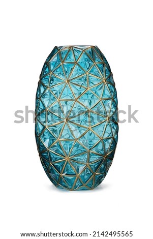 Subject shot of a blue faceted transparent vase made of tinted glass with golden enamel. The designer oval vase is isolated on the white background.