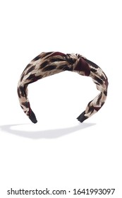 Subject Shot Of A Fabric Headband With A Knot And Beige And Brown Leopard Print. The Hair Holder Is Isolated On The White Background With Shadows.