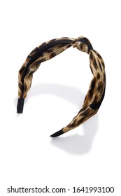 Subject Shot Of A Fabric Headband With A Knot And Black, Yellow And Brown Leopard Print. The Hair Holder Is Isolated On The White Background With Shadows.