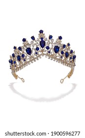 Subject Shot Of Golden Tiara Adorned With A Plenty Of Sapphire Gems And Clear Sparkling Rhinestones That Form Fanciful Pattern. The Luxury Queen Crown Is Isolated On The White Backdrop.