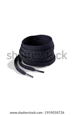 Subject shot of navy blue shoe strings with thin tips. Flat shoe laces are rolled into coil and isolated on the white background.