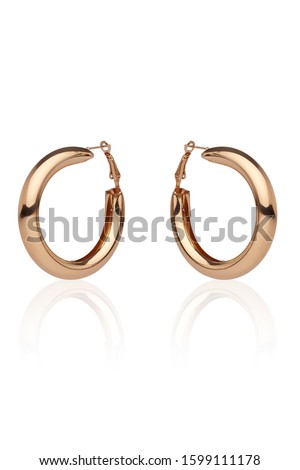 Subject shot of a pair of golden earrings isolated on the white background with reflexion. Each earring is made as a glossy puffed hoop.