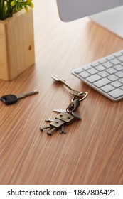 Subject Shot Of Retro Keychain Made As Bronze Robot On Coiled Leather Cord. The Stylish Keyring With Charm And Keys Is Located On The Wooden Table Near Computer In Office. 