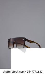 Subject shot square oversized sunglasses and thick brown spotted frame   gradient lenses  The sunglasses are isolated the white square the gray background  
