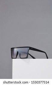 Subject shot square oversized sunglasses and thick black frame   silver mirror lenses  The sunglasses are isolated the white square the gray background  