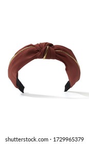 Subject Shot Of A Tile-red Fabric Headband With A Knot And Golden Piping. The Fashion Hair Accessory Is Isolated On The White Backdrop. 