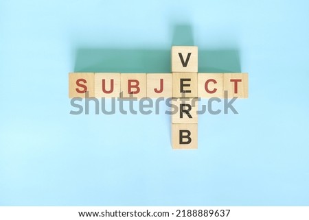 Subject verb agreement concept in English grammar education. Wooden block crossword puzzle flat lay in blue background