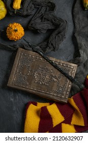 Subjects of the school of magic and pumpkins. Scarf, magic wand, book of spells on grey dark rag background.