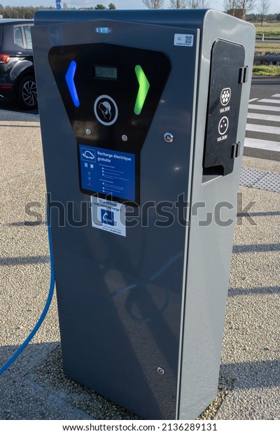 Sublaines, France - February 25, 2022: A static\
shot of a solid black Tesla Model 3 dual motor long range awd\
charging at the AC Freshmile charging station in a sunny winter\
day. Selective\
focus.