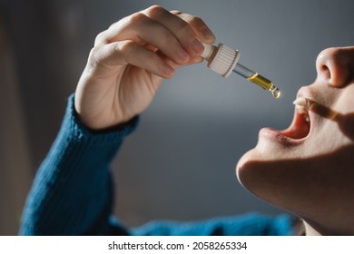 Sublingual cbd hemp oil - Woman taking cannabidiol under tongue for anxiety alternative treatment - Focus on hand holding dropper