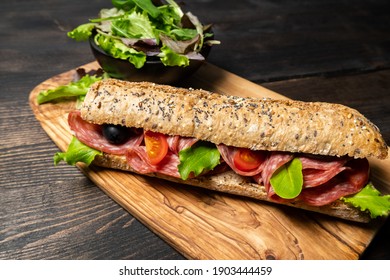 Submarine Salami Sandwich With Multigrain Bread Baguette With Green Lettuce And Tomato. Takeaway Takeout Food. Top View. Healthy Lunch Dinner