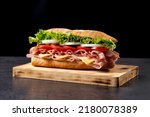 Submarine sandwich with ham, cheese, lettuce, tomatoes,onion, mortadella and sausage on wooden table
