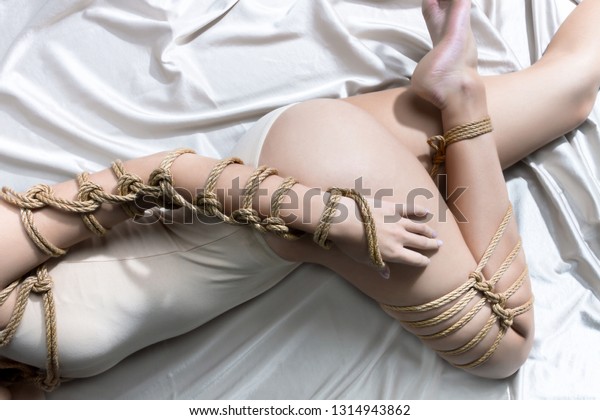 Submission slave woman bound in erotic fashion\
style rope shibari kinbaku Japanese bondage knot lie on silk bed.\
Bdsm sadomasochism mistress master dominant fetish punishment\
flogging sadism\
concept.