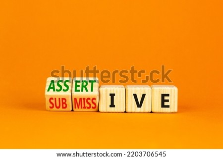 Submissive or assertive symbol. Concept words Submissive and assertive on wooden cubes. Beautiful orange background. Business, psychological submissive assertive concept. Copy space.
