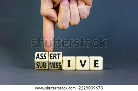 Submissive or assertive symbol. Concept words Submissive and assertive on wooden cubes. Businessman hand. Beautiful grey background. Business, psychological submissive assertive concept. Copy space.