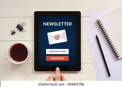 Subscribe newsletter concept on tablet screen with office objects on white wooden table. All screen content is designed by me. Flat lay - Shutterstock ID 583402786