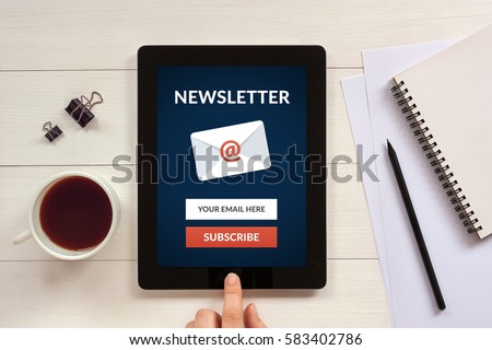 Subscribe newsletter concept on tablet screen with office objects on white wooden table. All screen content is designed by me. Flat lay