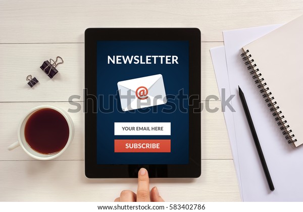 Subscribe newsletter concept on tablet screen with\
office objects on white wooden table. All screen content is\
designed by me. Flat\
lay
